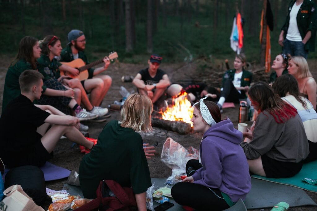 Kampvuur Een diverse groep genietend van samenhorigheid, gitaar en een kampvuur in de avond.